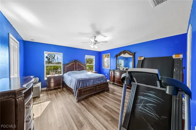 a bedroom with a bed a dresser and wooden floor