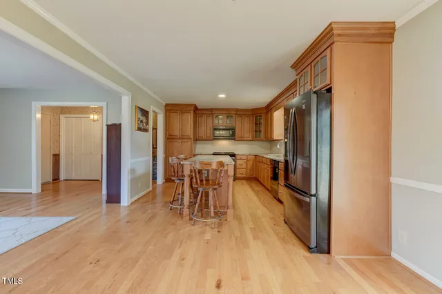 a open kitchen with stainless steel appliances granite countertop a refrigerator and a table