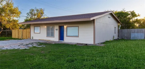 a view of a house with a yard plants and large tree
