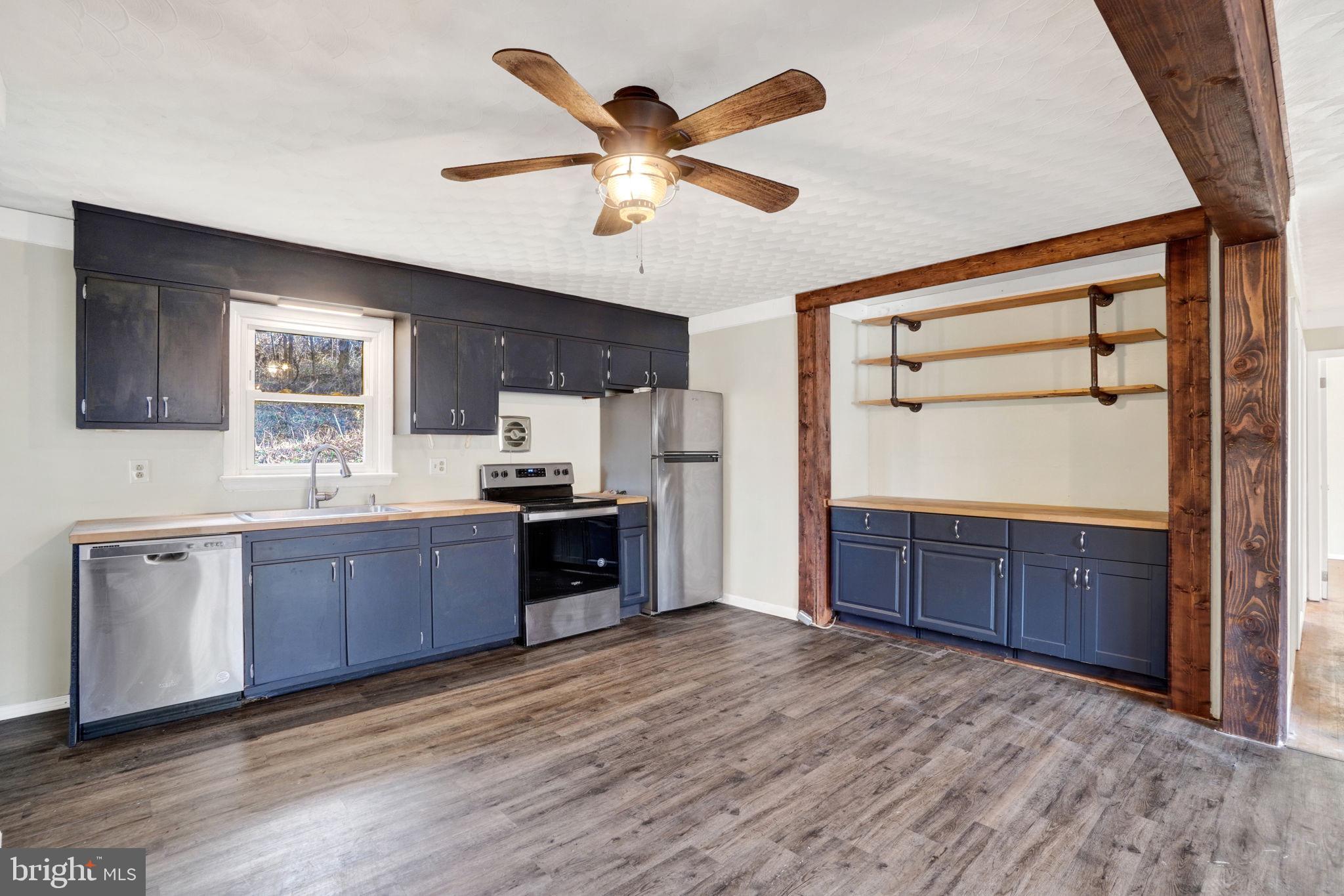 5714 Spruce Road Felton, PA 17322 - Photo 11 of 33 a kitchen with stainless steel appliances kitchen island granite countertop a stove a sink and a refrigerator with wooden floors