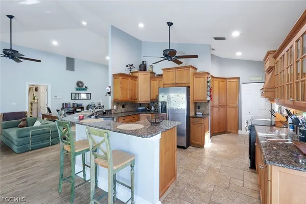 a kitchen with stainless steel appliances kitchen island granite countertop a sink a stove and a refrigerator