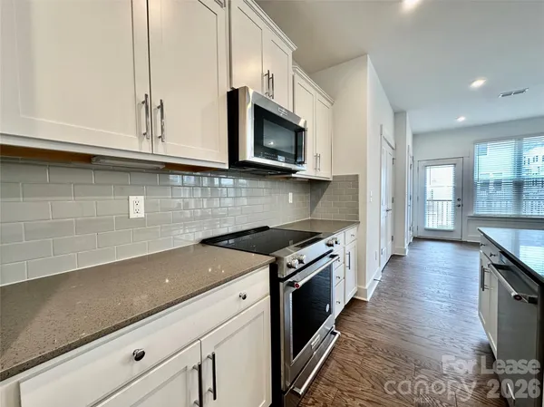 a kitchen with stainless steel appliances granite countertop a sink a stove and a microwave