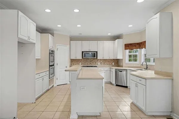 a kitchen with a sink a counter top space stainless steel appliances and cabinets