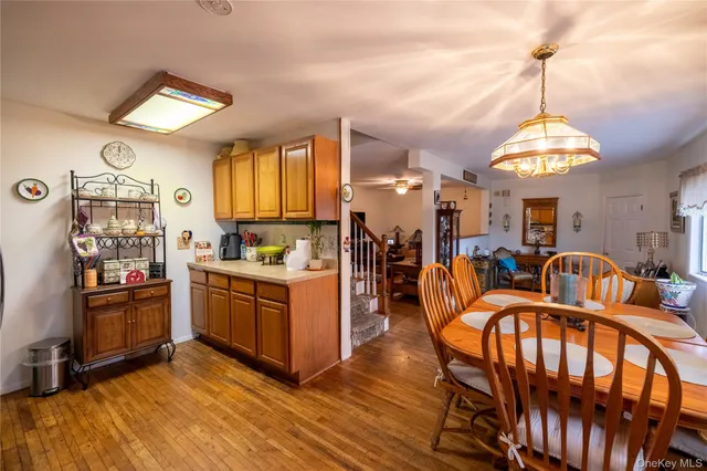 a very nice looking dining room with kitchen island granite countertop a stove a refrigerator a oven a dining table and chairs with wooden floor