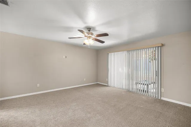 an empty room with chandelier fan and windows