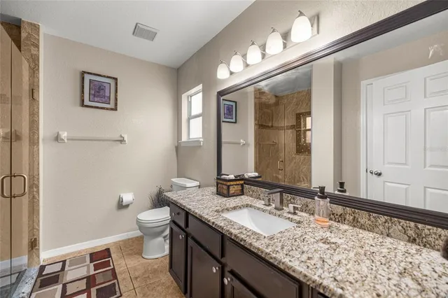 a bathroom with a granite countertop sink a toilet and a mirror
