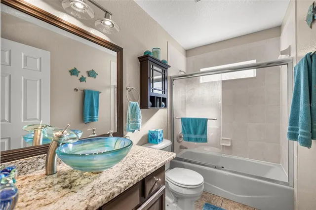 a bathroom with a granite countertop sink a toilet a mirror and shower