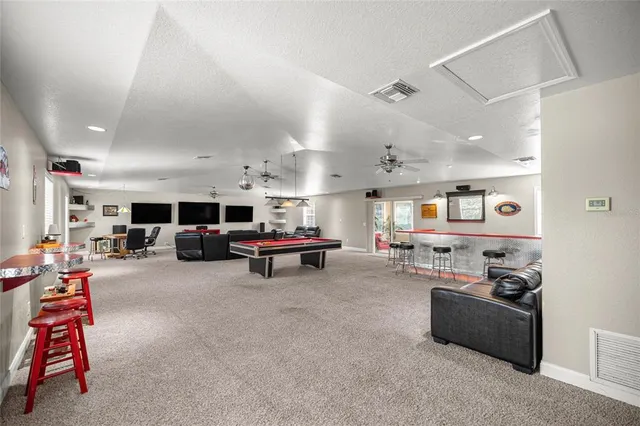a living room with furniture pool table and windows