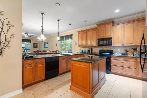 a kitchen with stainless steel appliances granite countertop a stove top oven a sink dishwasher a dining table and chairs with wooden floor