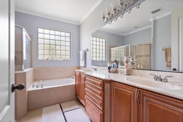 a bathroom with a tub a sink double vanity and a mirror