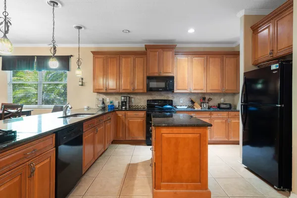a kitchen with stainless steel appliances granite countertop a refrigerator a sink dishwasher a stove and a microwave oven on the granite countertops