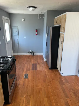 a view of a kitchen with refrigerator and wooden floor