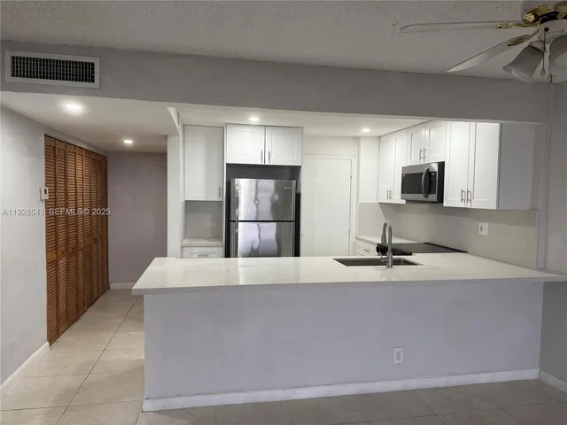 a large kitchen with kitchen island granite countertop a refrigerator a stove and a sink