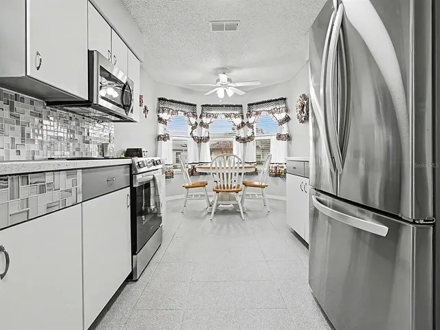 a kitchen with stainless steel appliances a refrigerator sink and white cabinets