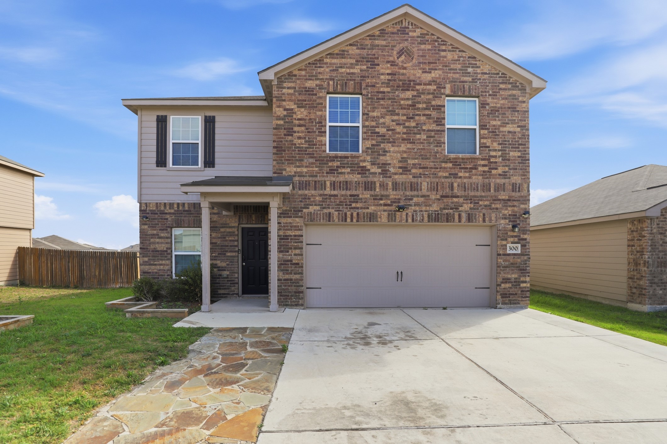 Front view of the home with brick siding, driveway, and an attached garage