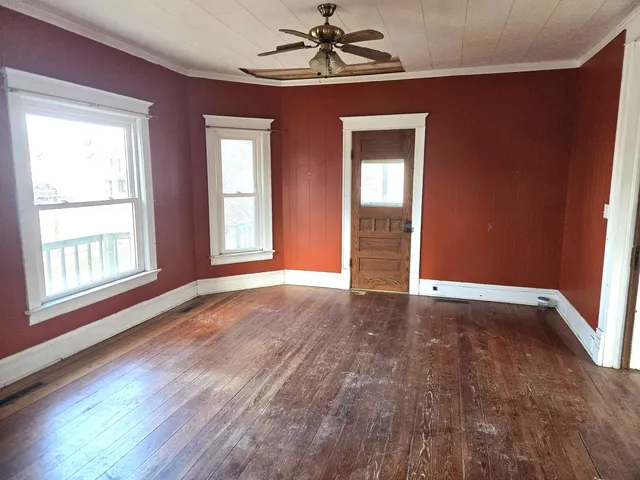 a view of an empty room with a window and wooden floor