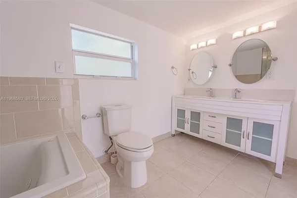 a spacious bathroom with a double vanity sink a toilet and a mirror