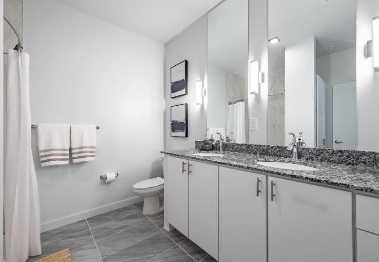 750 Avondale Creek Dr., Unit 206 Decatur, GA 30032 - Photo 23 of 35 a bathroom with a granite countertop sink a toilet and a mirror