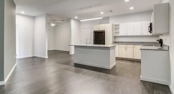 a kitchen with stainless steel appliances granite countertop a stove top oven a sink and white cabinets with wooden floor