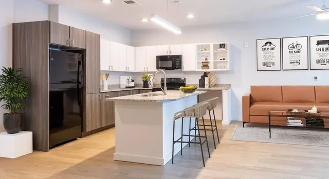 a living room with stainless steel appliances kitchen island granite countertop a refrigerator a stove a sink a dining table and chairs