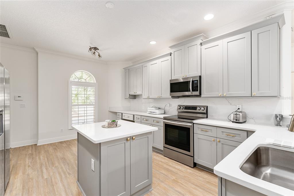 4987 Southwest 63rd Loop Ocala, FL 34474 - Photo 21 of 56 a kitchen with a sink a stove a microwave and wooden cabinets