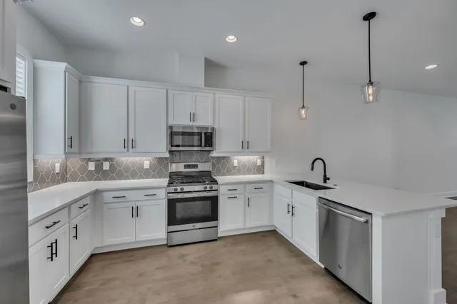 a kitchen with stainless steel appliances granite countertop a sink stove and cabinets