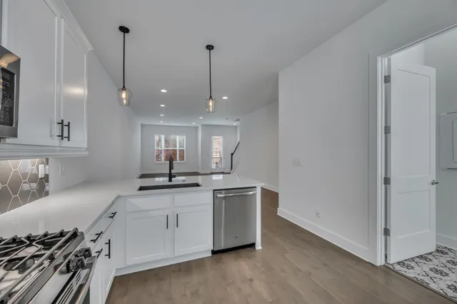 a kitchen with stainless steel appliances granite countertop a sink a stove and a wooden floor