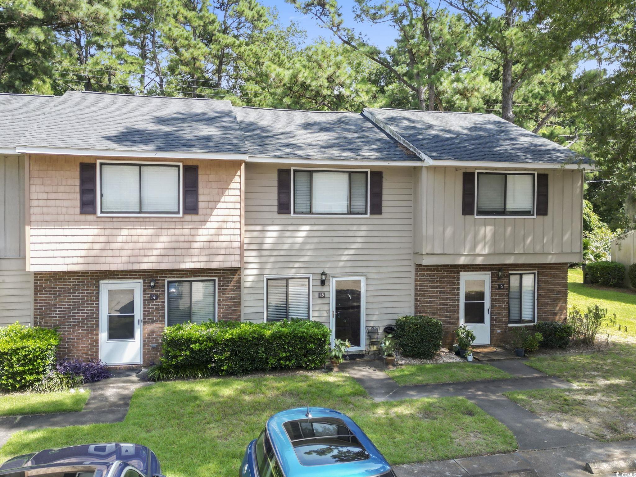 Colonial-style house with brick siding, a front lawn, and a shingled roof
