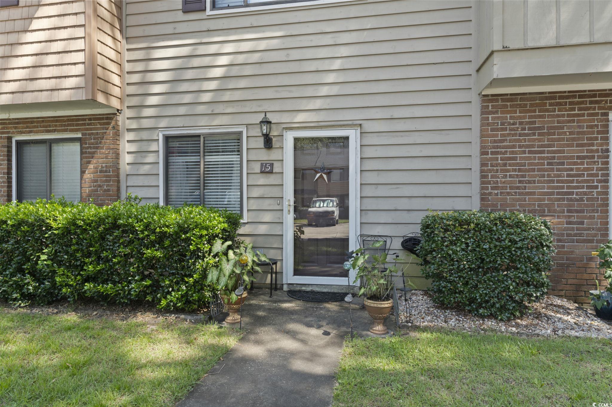 55 Beaver Pond Loop, Unit 15 Pawleys Island, SC 29585 - Photo 21 of 24 Doorway to property with brick siding and a yard