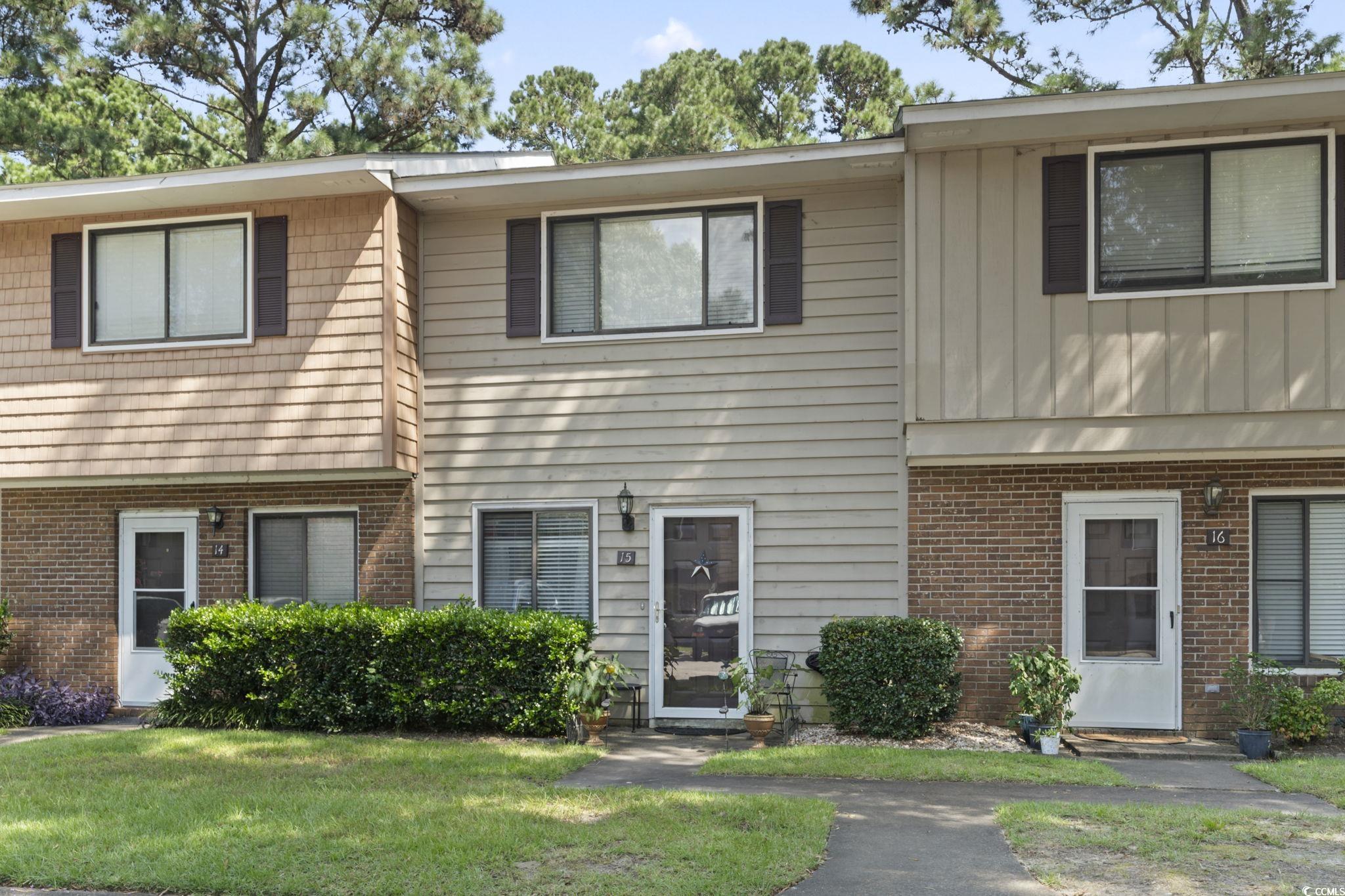 55 Beaver Pond Loop, Unit 15 Pawleys Island, SC 29585 - Photo 22 of 24 View of front of house featuring brick siding, a front lawn, and board and batten siding