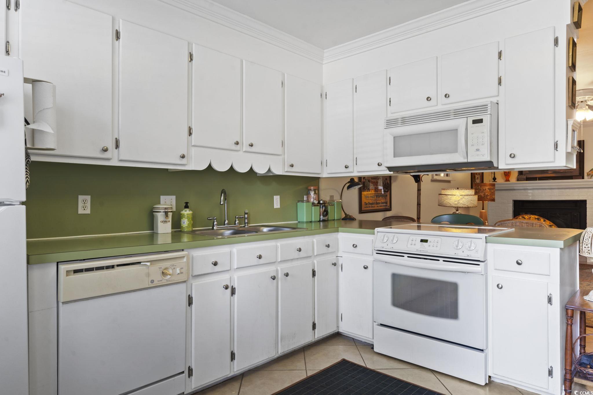 55 Beaver Pond Loop, Unit 15 Pawleys Island, SC 29585 - Photo 5 of 24 Kitchen featuring white appliances, white cabinetry, light tile patterned flooring, ornamental molding, and light countertops