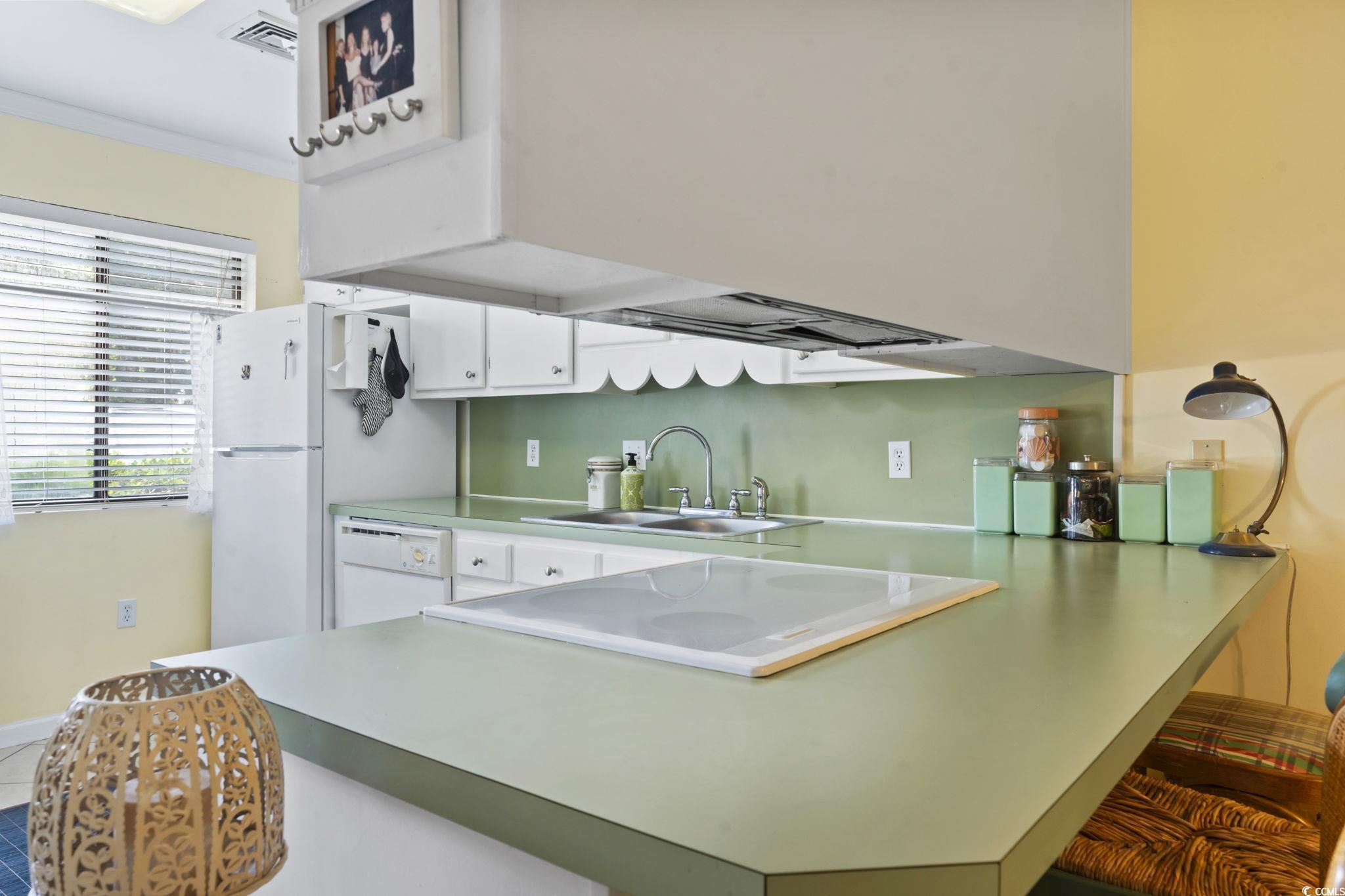 55 Beaver Pond Loop, Unit 15 Pawleys Island, SC 29585 - Photo 6 of 24 Kitchen featuring a breakfast bar, a peninsula, white cabinets, light countertops, and dishwasher