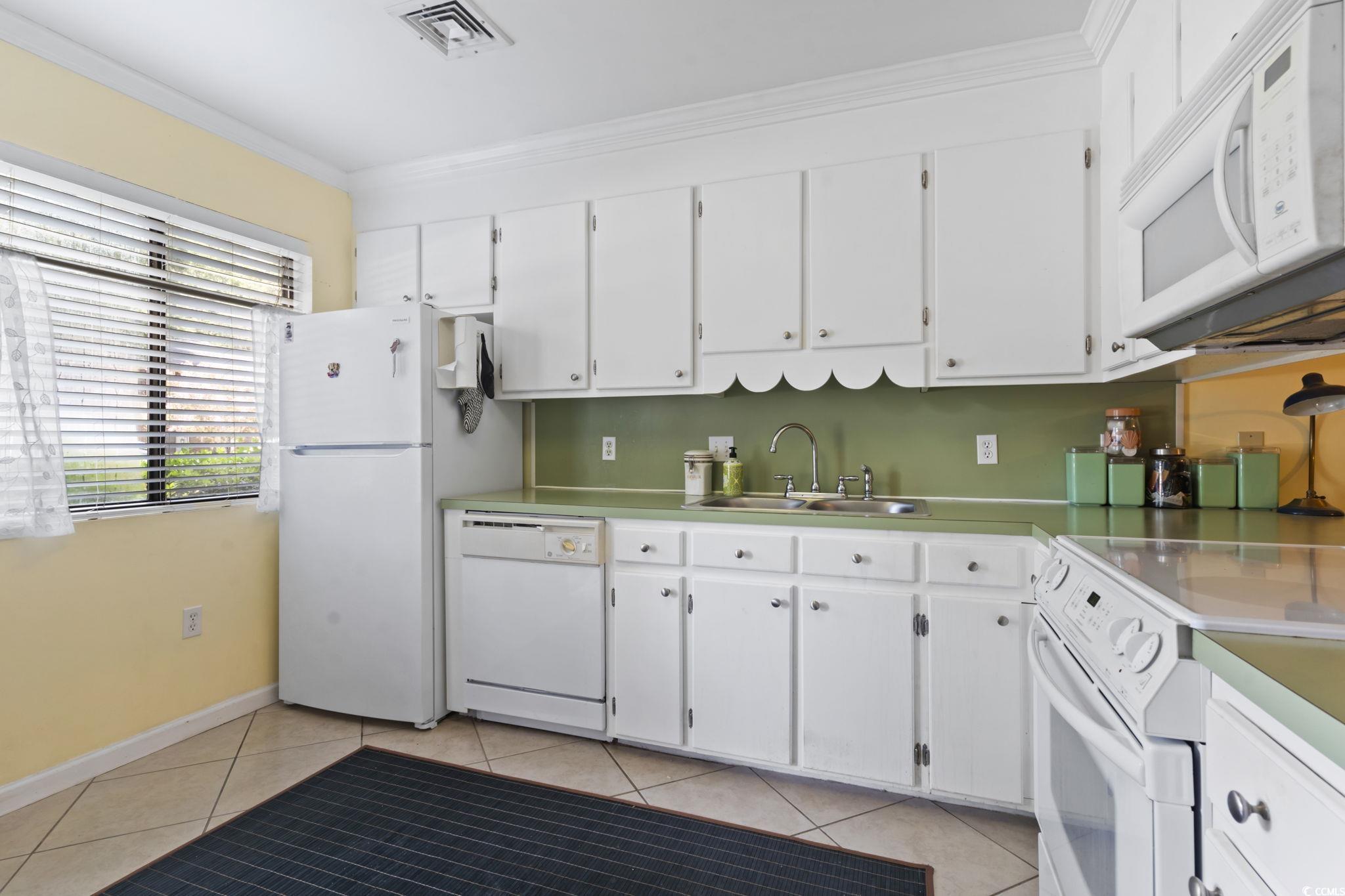 55 Beaver Pond Loop, Unit 15 Pawleys Island, SC 29585 - Photo 7 of 24 Kitchen with white appliances, ornamental molding, white cabinetry, light tile patterned floors, and light countertops