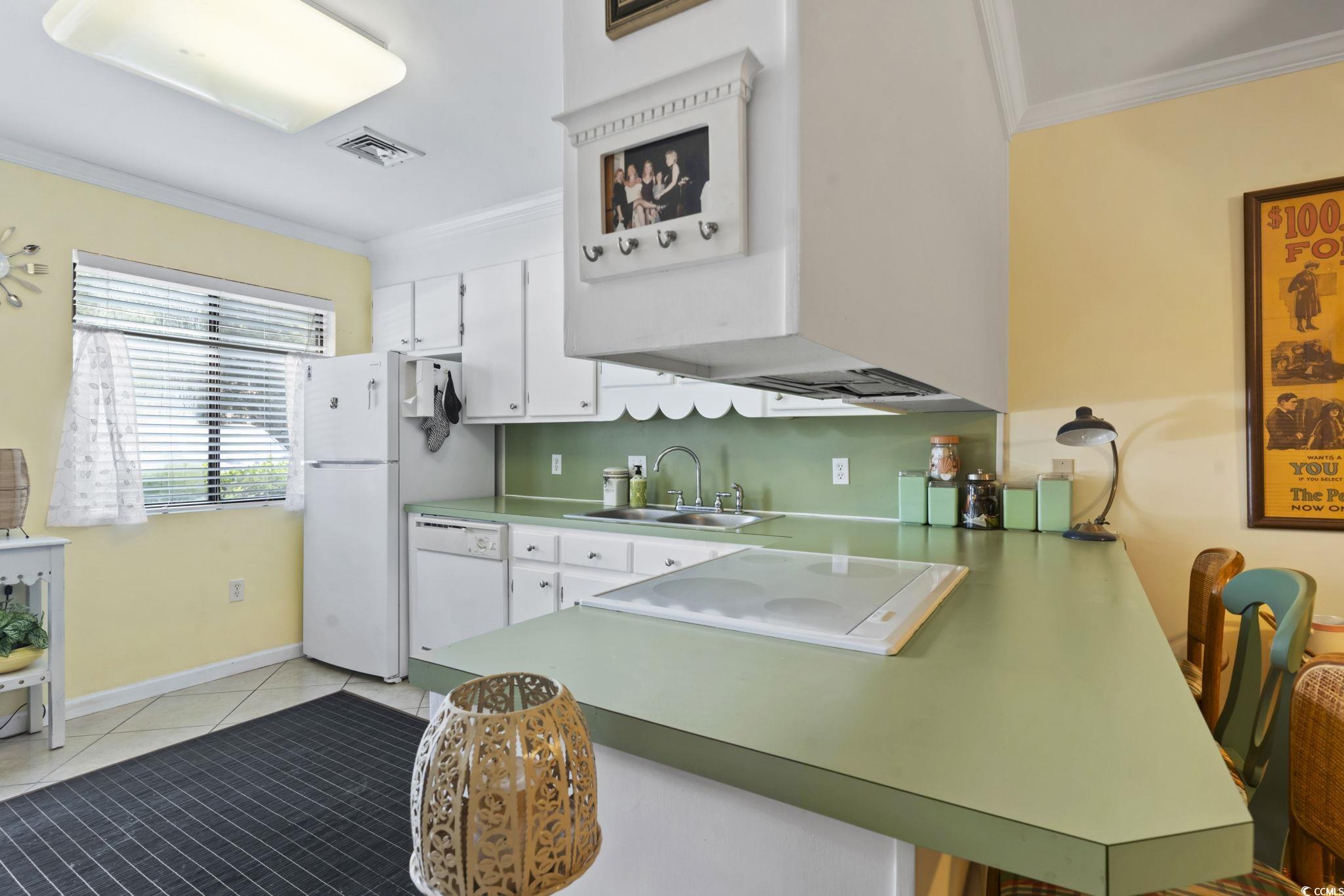 55 Beaver Pond Loop, Unit 15 Pawleys Island, SC 29585 - Photo 8 of 24 Kitchen with ornamental molding, a peninsula, white cabinetry, light tile patterned floors, and a kitchen bar