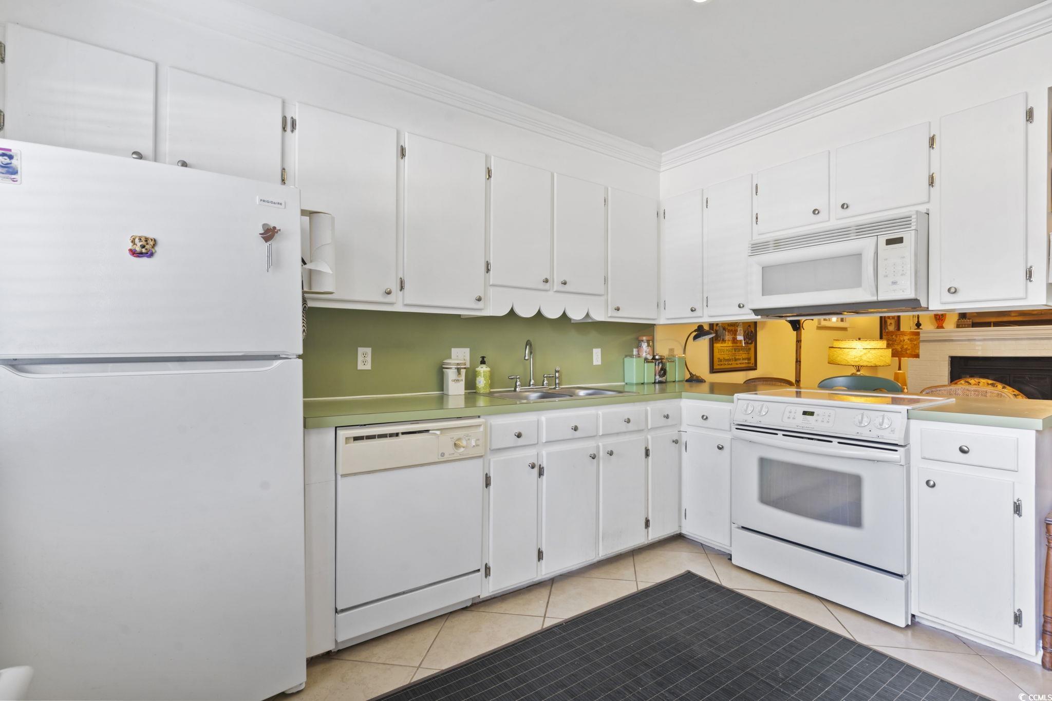 55 Beaver Pond Loop, Unit 15 Pawleys Island, SC 29585 - Photo 9 of 24 Kitchen featuring white appliances, white cabinets, crown molding, light tile patterned floors, and light countertops