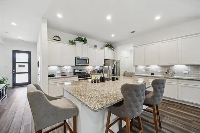 a kitchen with stainless steel appliances granite countertop a stove a sink dishwasher and a refrigerator with wooden floor