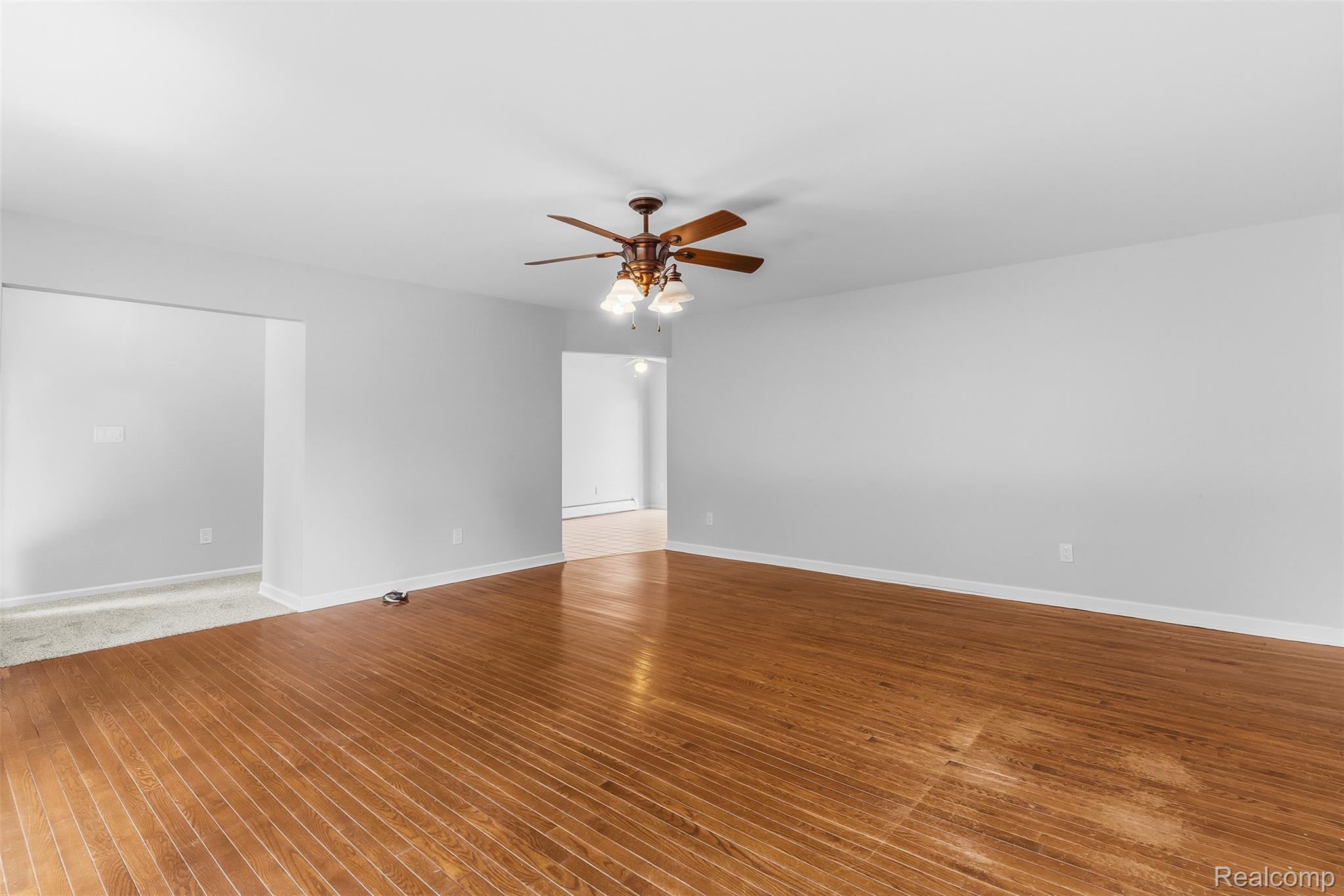 9200 Hickory Ridge Road Holly, MI 48442 - Photo 11 of 33 Spacious room with wood-finish flooring, light grey wall paint, and a ceiling fan with integrated lighting
