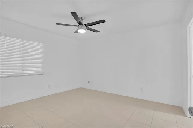 an empty room with a window and a fan