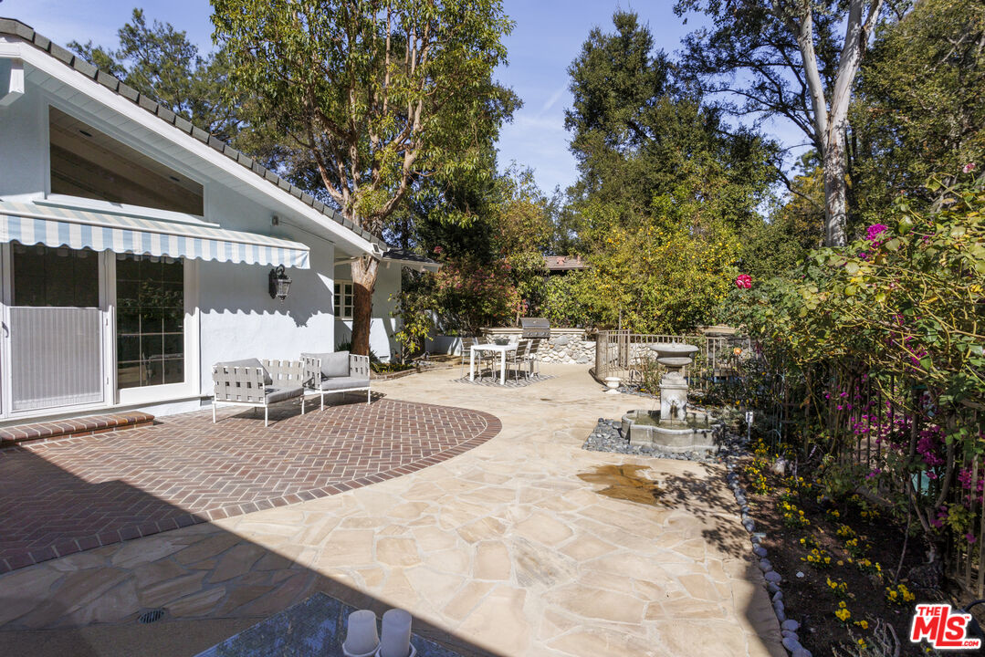 15946 Valley Wood Road Sherman Oaks, CA 91403 - Photo 22 of 23 a view of a patio with couches and table and chairs under an umbrella