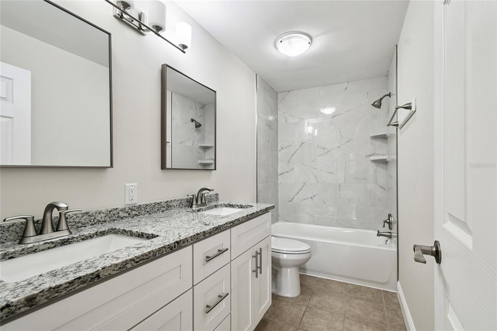 623 Palm Boulevard Dunedin, FL 34698 - Photo 12 of 55 a bathroom with a granite countertop sink double vanity granite tub shower and a mirror
