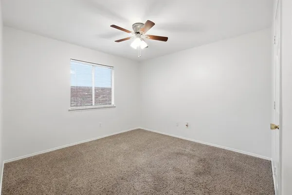 an empty room with chandelier fan and windows
