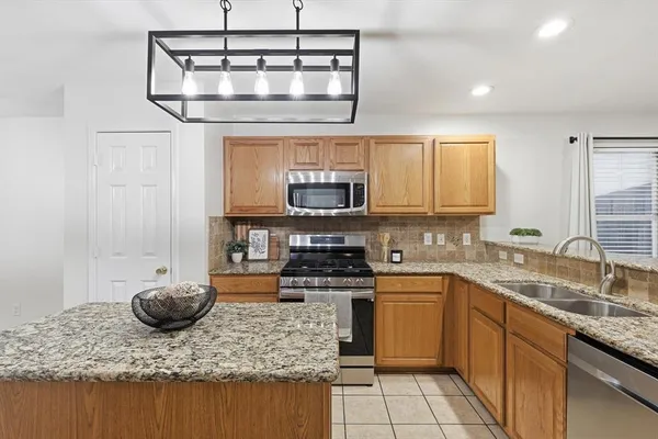 a kitchen with stainless steel appliances granite countertop a sink a stove and cabinets