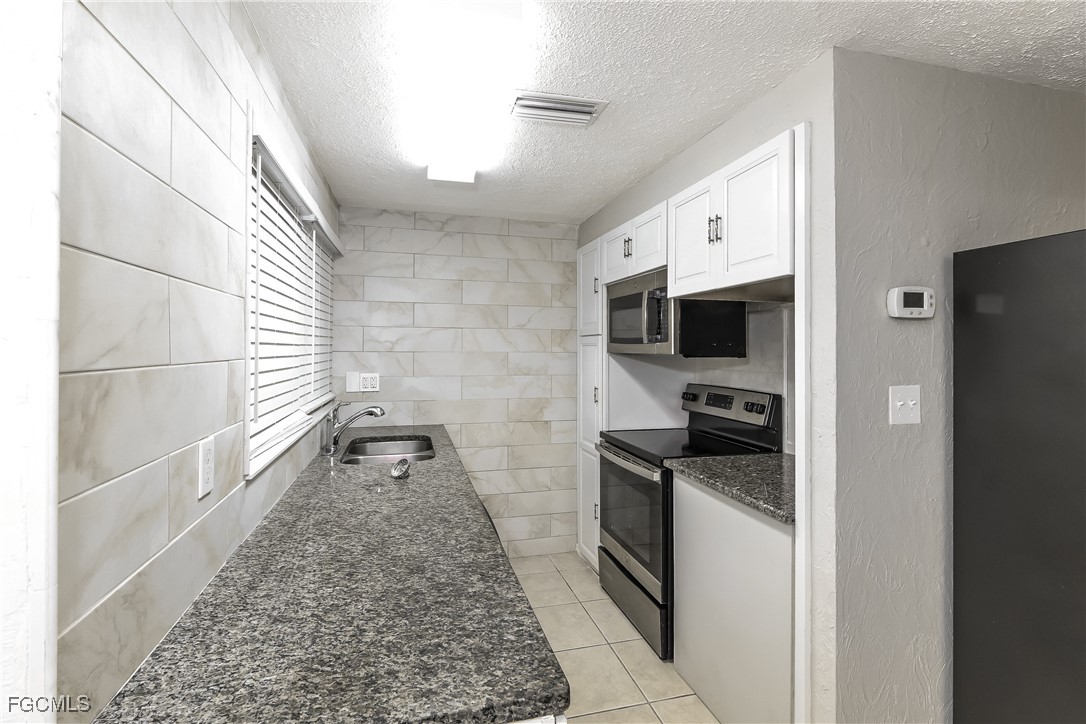 4215 Tarpon Road Venice, FL 34293 - Photo 5 of 16 a kitchen with granite countertop a sink and a stove top oven