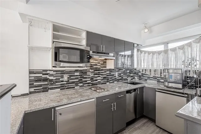 a kitchen with stainless steel appliances granite countertop a sink stove and microwave