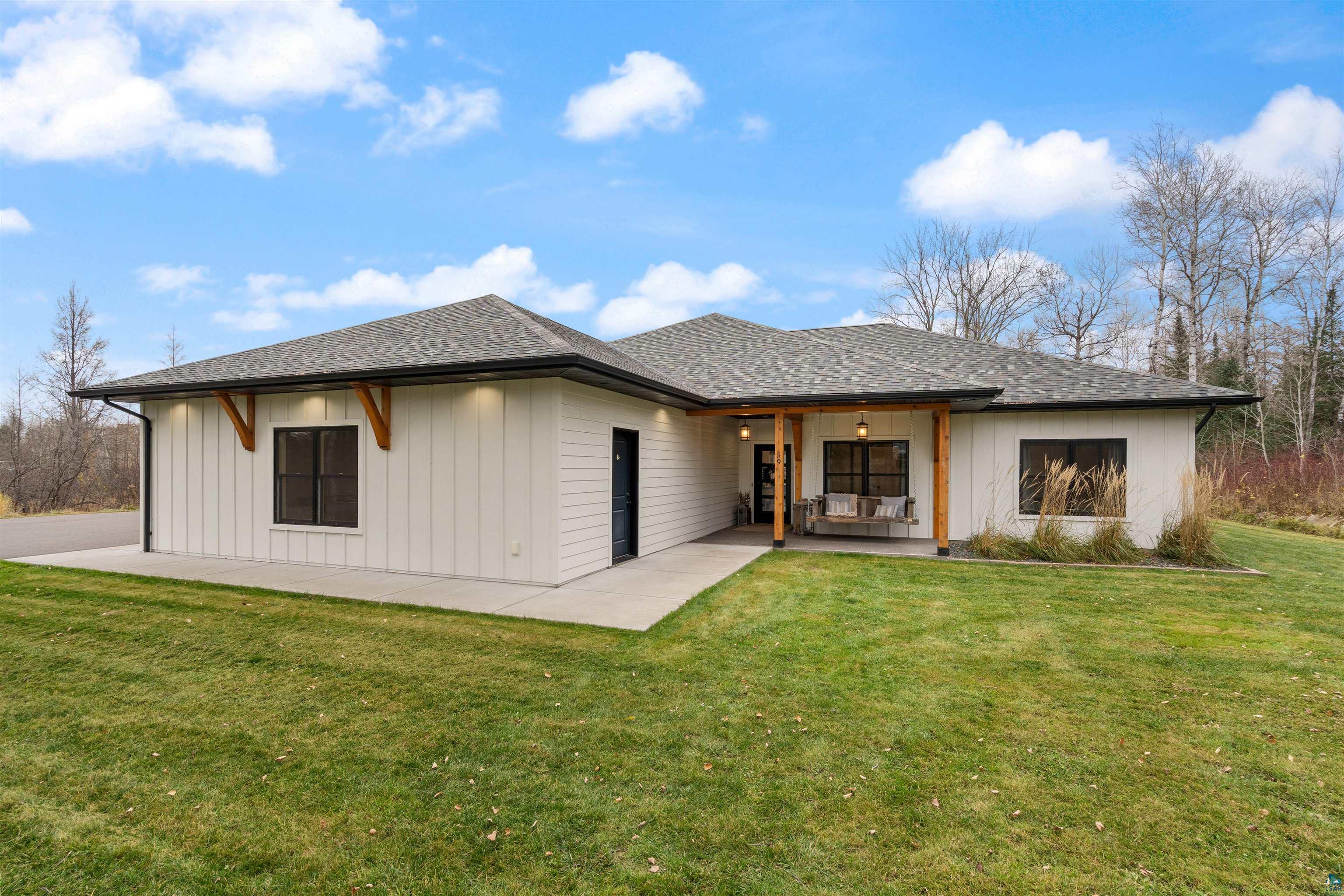Rear view of house with roof with shingles, a yard, and covered porch