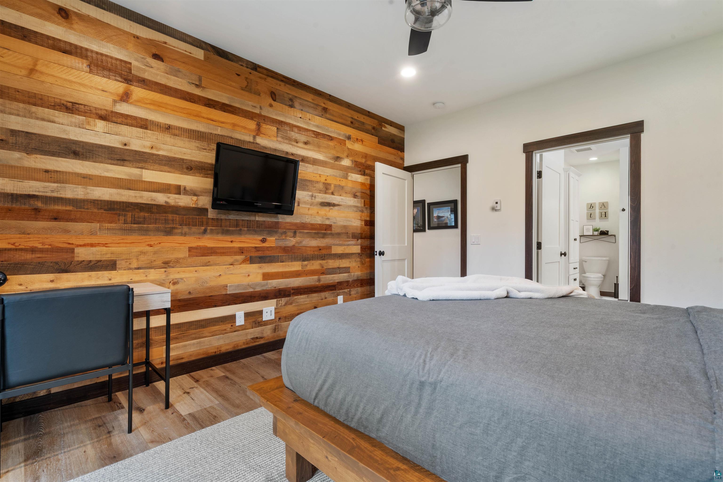 59 East Riverside Road Esko, MN 55733 - Photo 15 of 48 Bedroom featuring wooden walls, light wood-style floors, ceiling fan, recessed lighting, and ensuite bathroom
