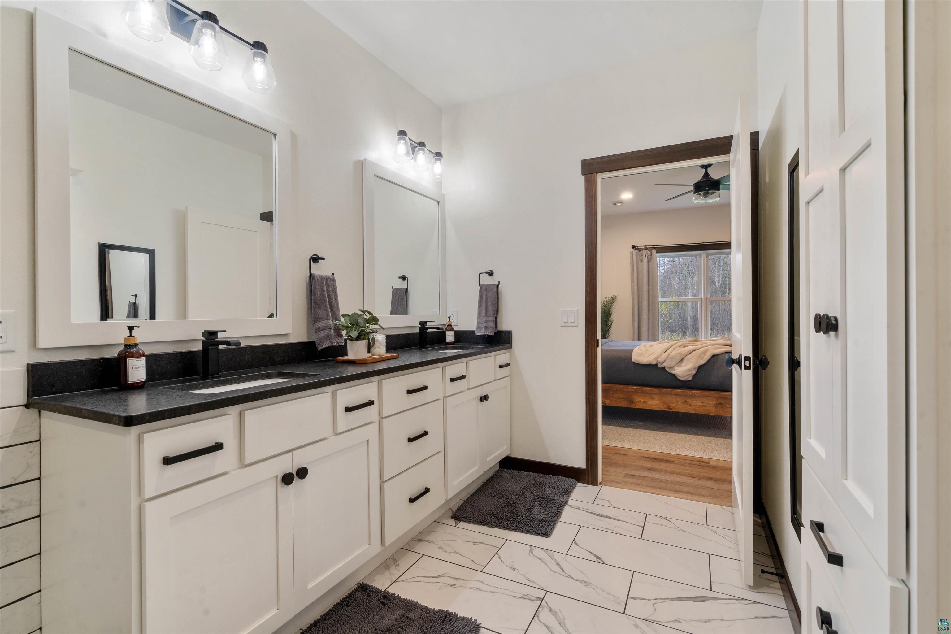 59 East Riverside Road Esko, MN 55733 - Photo 31 of 48 Ensuite bathroom featuring double vanity, light marble finish flooring, and a ceiling fan