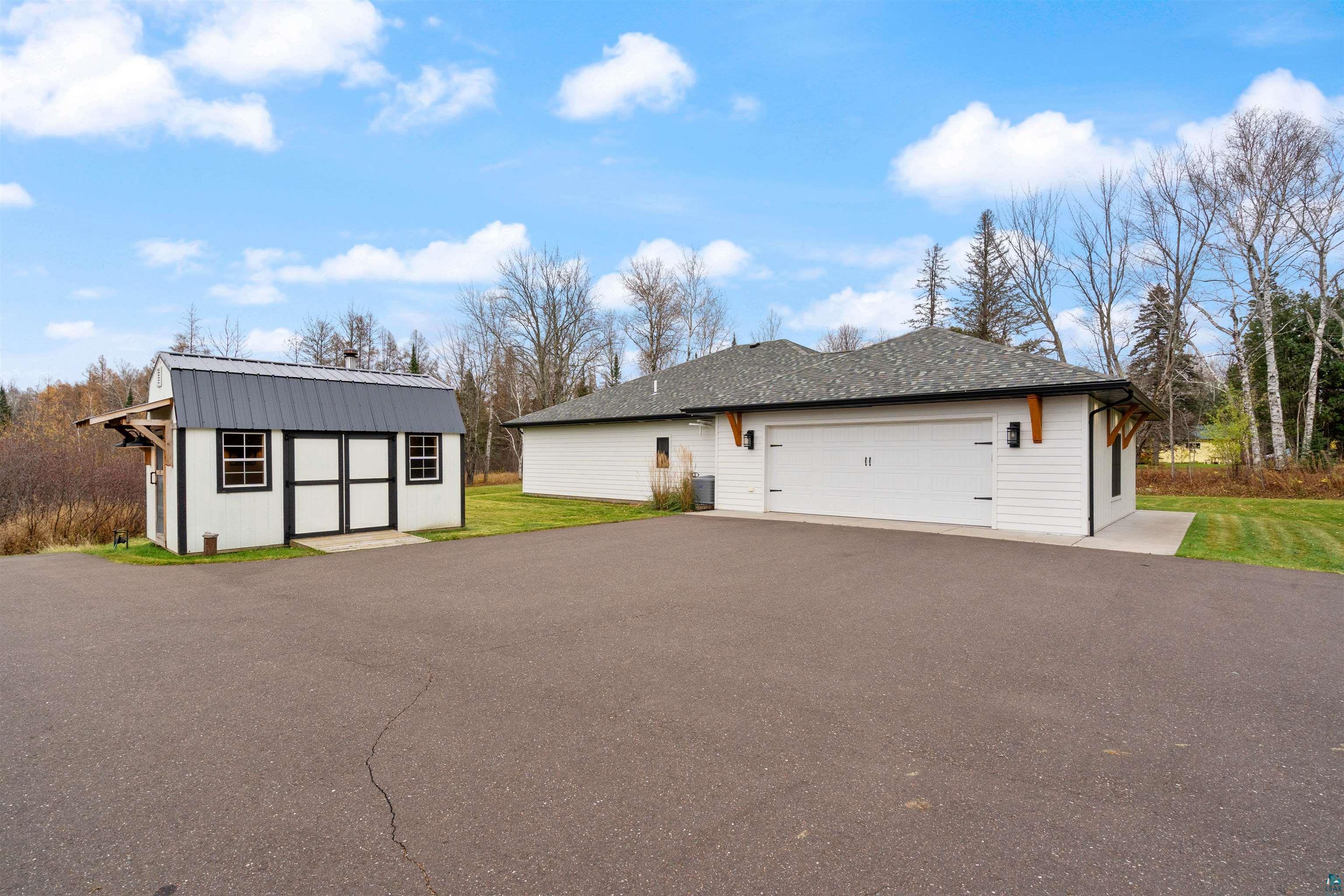 59 East Riverside Road Esko, MN 55733 - Photo 35 of 48 View of home's exterior featuring an outdoor structure, a lawn, asphalt driveway, and an attached garage
