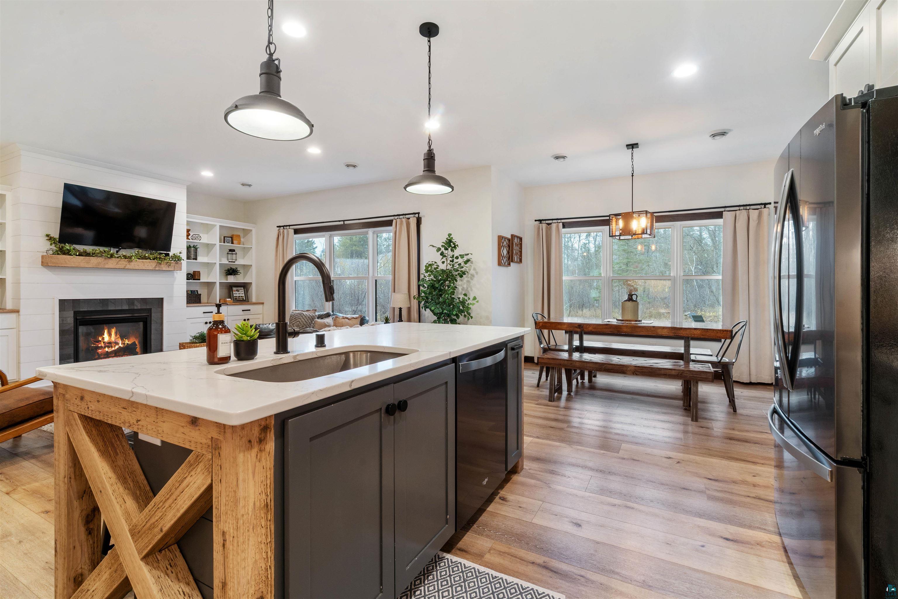 59 East Riverside Road Esko, MN 55733 - Photo 10 of 48 Kitchen with stainless steel appliances, light stone countertops, light wood-style floors, a kitchen island with sink, and hanging light fixtures