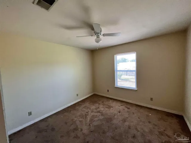 an empty room with a ceiling fan and a window